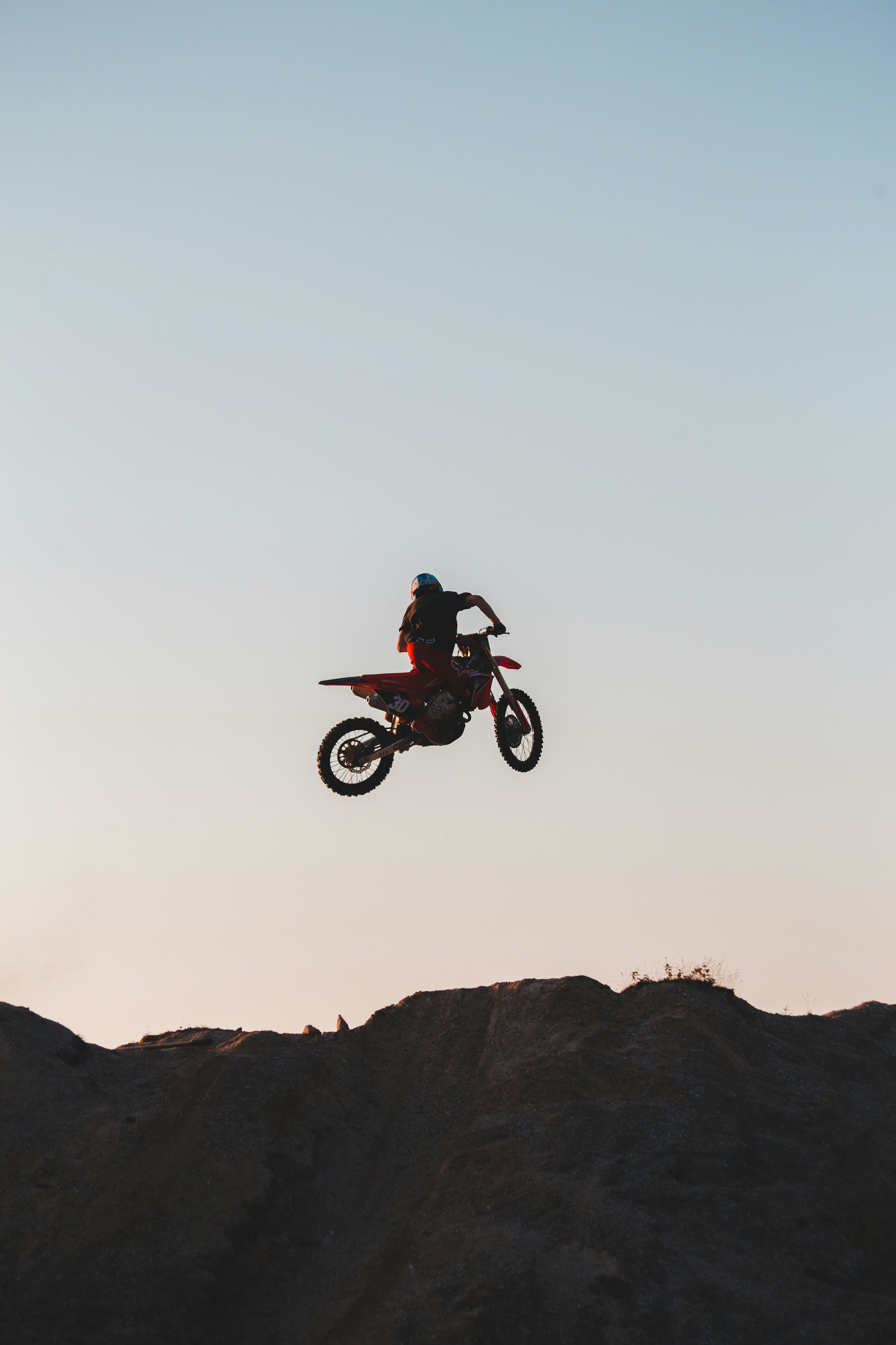 man riding motocross dirt bike on brown rocky mountain during daytime